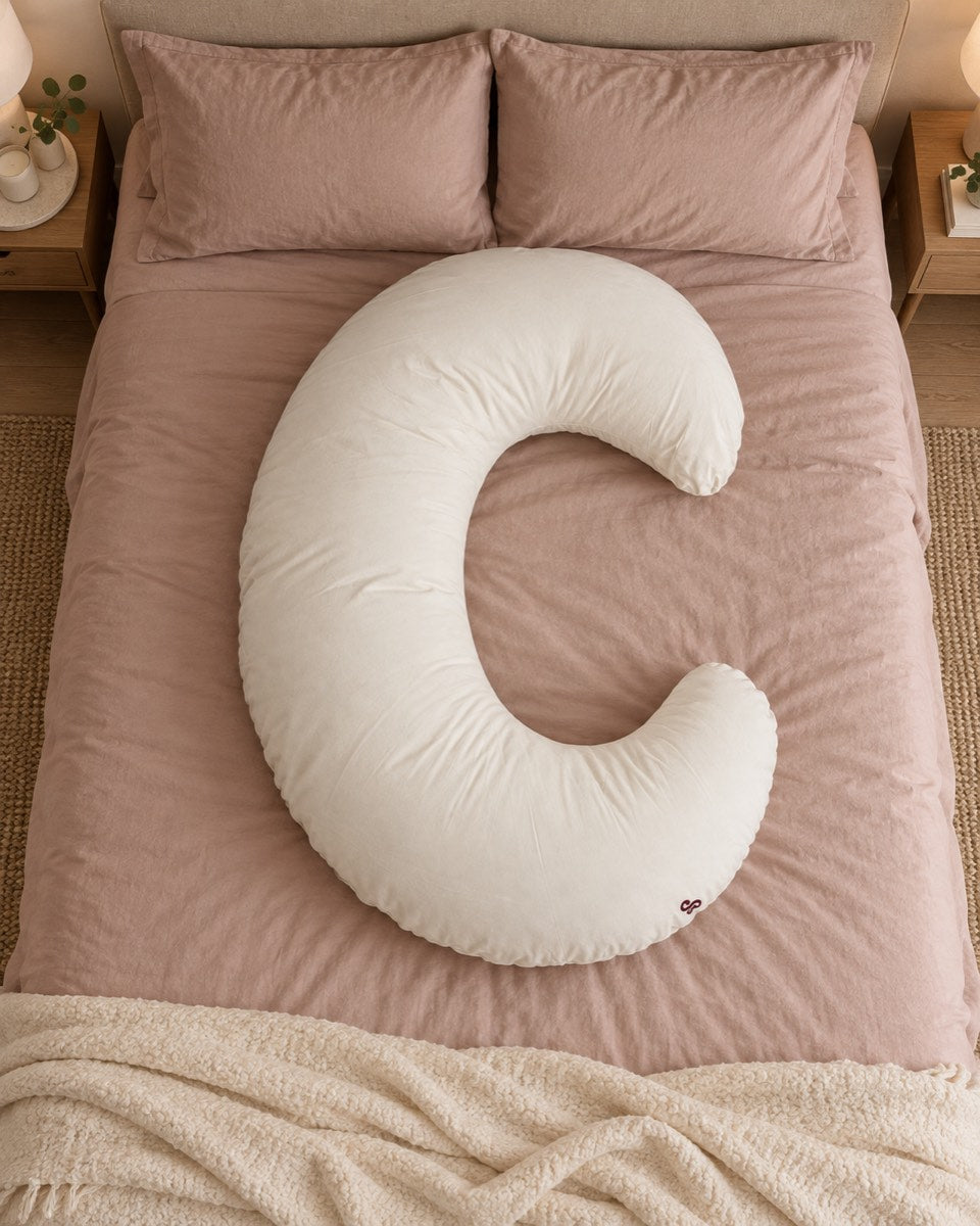 Full ivory C-shaped Sunday Hug pillow on dusty rose bedding for scale